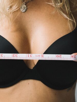 Close-up of a woman measuring her bust with tape for the perfect bra fit.