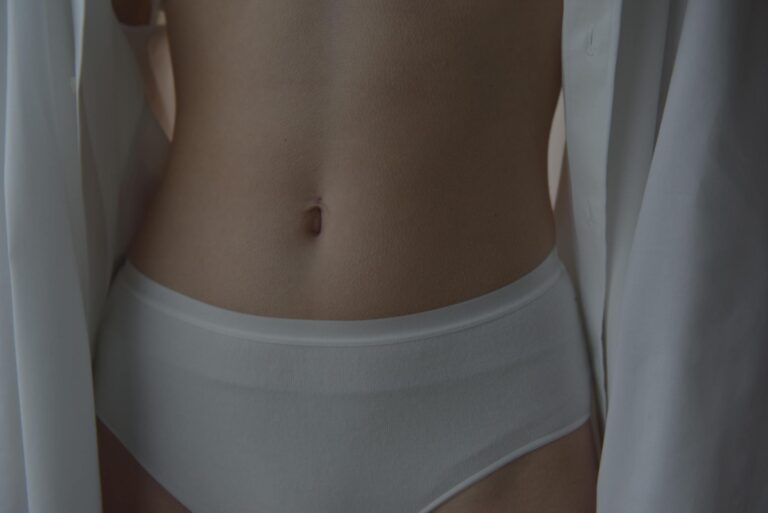 Intimate close-up image showcasing a woman's waist and belly button in white lingerie for fashion aesthetics.